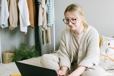 Woman working from home with laptop on bed