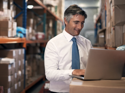 Man on a laptop in a warehouse representing logistics sector